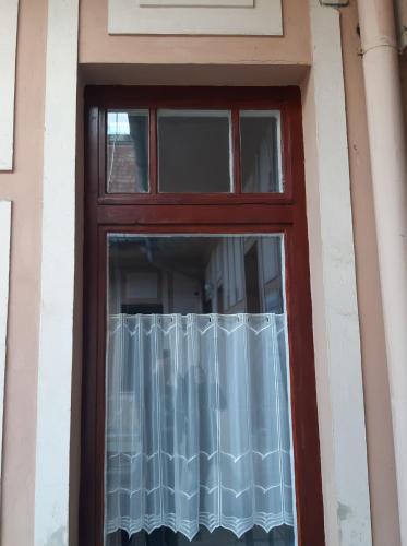 a red door with a window with a curtain at ANKER SILVER DREAM in Kaposvár