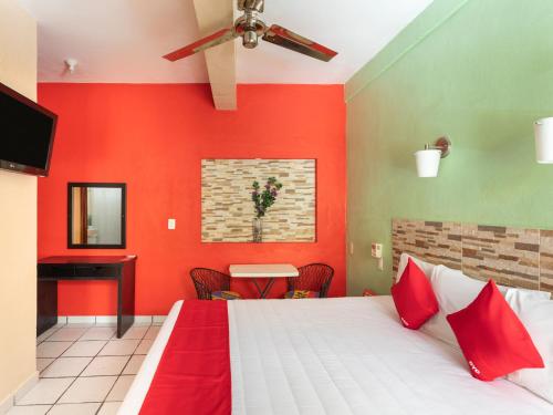 a bedroom with red walls and a bed and a table at Hotel Costa Azul in Chetumal