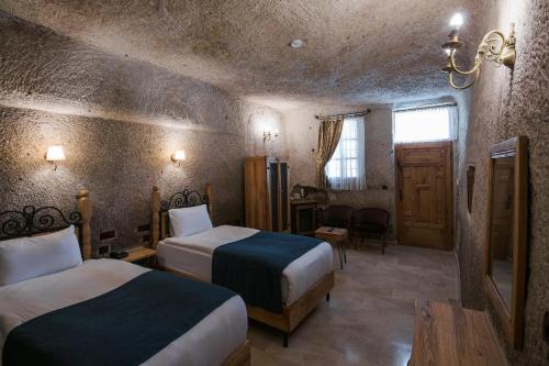 a hotel room with two beds and a table and a window at Lunar Cappadocia Hotel in Goreme