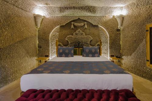 a bedroom with a king sized bed in a stone wall at Lunar Cappadocia Hotel in Goreme