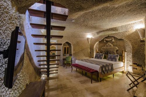 a bedroom with a bed and a staircase in a cave at Lunar Cappadocia Hotel in Goreme