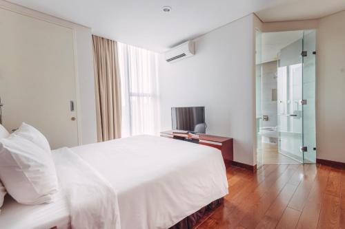 a bedroom with a large white bed and a mirror at SILA Urban Living in Ho Chi Minh City
