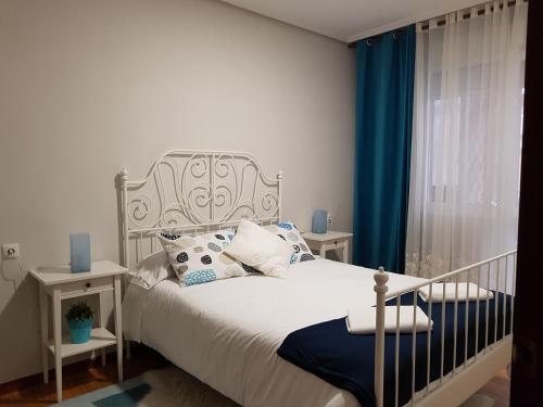 a bedroom with a white bed with blue curtains at Apartamento COSTA VASCA Las Arenas Getxo in Getxo