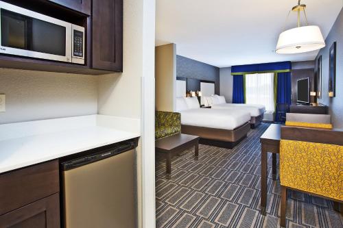a hotel room with a bed and a room with a kitchen at Holiday Inn Express Hotel & Suites Ann Arbor West by IHG in Ann Arbor
