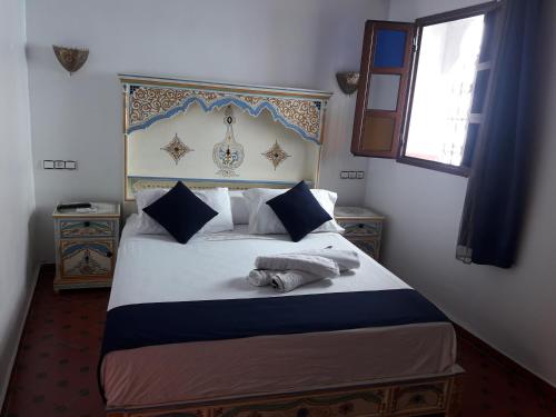a bedroom with a bed with a blue and white headboard at Casa El Haouta in Chefchaouene