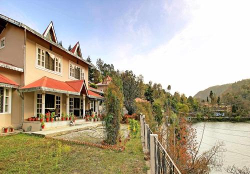 ein Haus neben einem Wasserkörper in der Unterkunft Neelesh Inn- A Luxury Lake View Hotel- 20 kms from Nainital in Bhīm Tāl