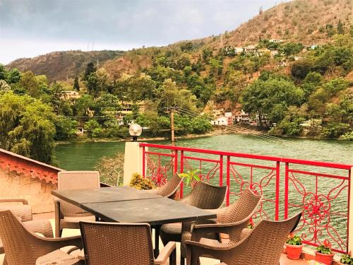 a table and chairs on a balcony overlooking a river at Neelesh Inn- A Luxury Lake View Hotel- 20 kms from Nainital in Bhīm Tāl