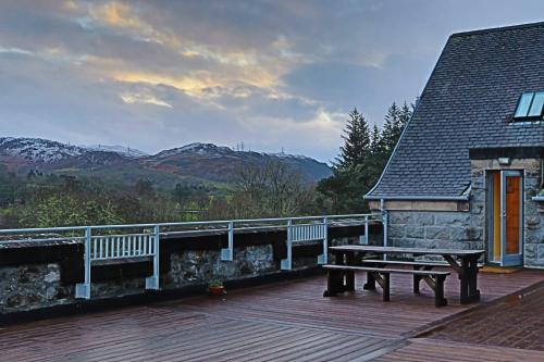 a wooden deck with a bench on top of a house at The Highland Club in Fort Augustus