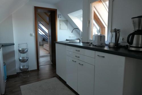 eine Küche mit weißen Schränken, einem Waschbecken und einem Fenster in der Unterkunft "Haus am Deich" in Cuxhaven