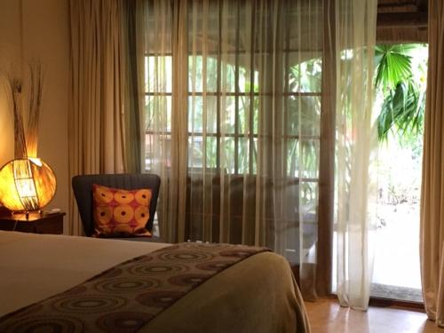 1 dormitorio con 1 cama, 1 silla y 1 ventana en Afrikhaya Guest House, en St Lucia