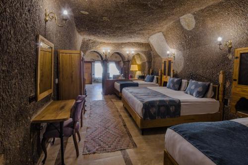 a bedroom with three beds and a table and chairs at Lunar Cappadocia Hotel in Goreme