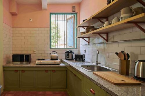 a kitchen with green cabinets and a sink and a window at Chendela Yogyakarta in Yogyakarta