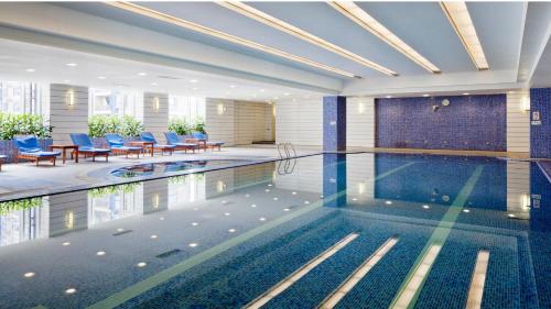 a swimming pool with chairs and tables in a building at Crowne Plaza Shanghai Pudong, an IHG Hotel in Shanghai