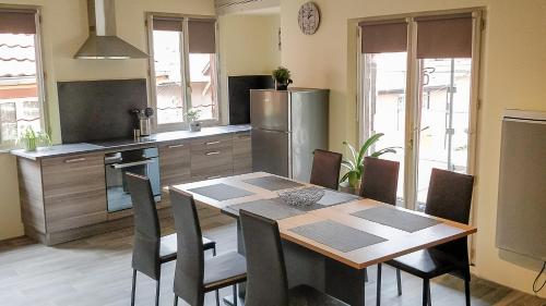 cocina con mesa, sillas y nevera en Le Familial, en Kintzheim