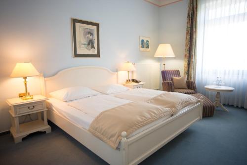 a bedroom with a large white bed and a chair at Trip Inn PostHotel Düren in Düren - Eifel