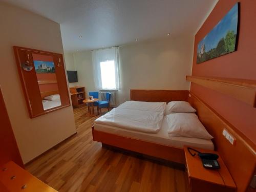 a small bedroom with a bed and a mirror at Hotel-Gasthof Zum Freigericht in Alzenau
