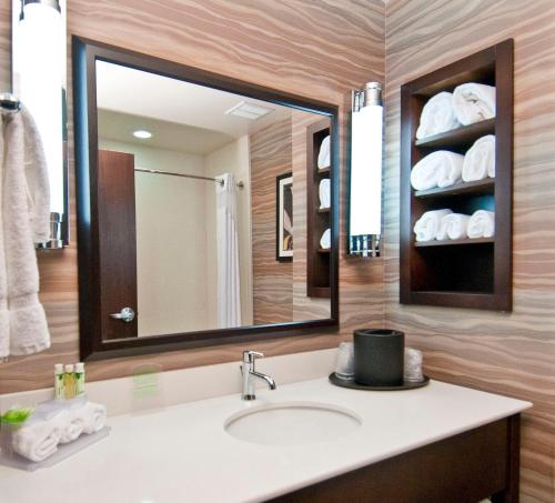 a bathroom with a sink and a mirror and towels at Holiday Inn Express & Suites San Antonio SE by AT&T Center, an IHG Hotel in San Antonio