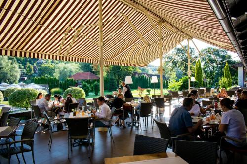 a group of people sitting at tables in a restaurant at Hotel Gradina Morii in Sighetu Marmaţiei