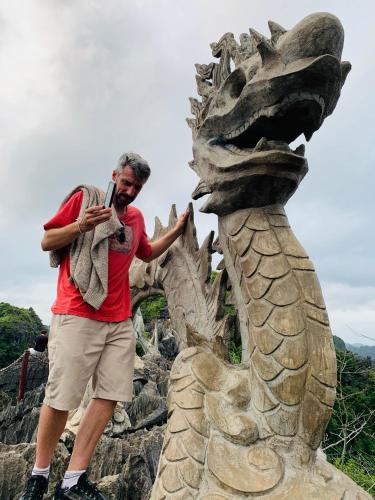 a man talking on a cell phone next to a statue at Tuan Nam Homestay in Ninh Binh