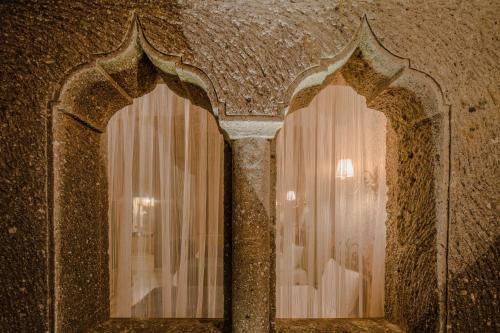 two windows in a stone wall with a reflection of a person in them at Lunar Cappadocia Hotel in Goreme