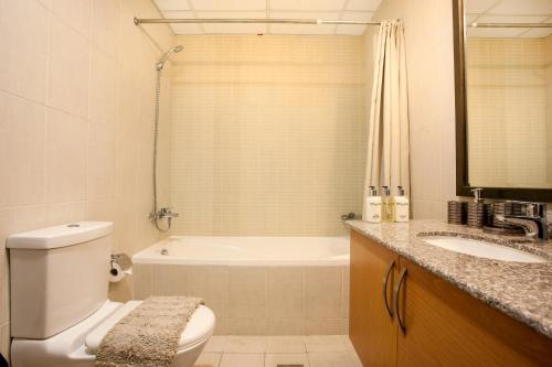 a bathroom with a toilet and a tub and a sink at Staycae Holiday Homes - Suburbia in Dubai