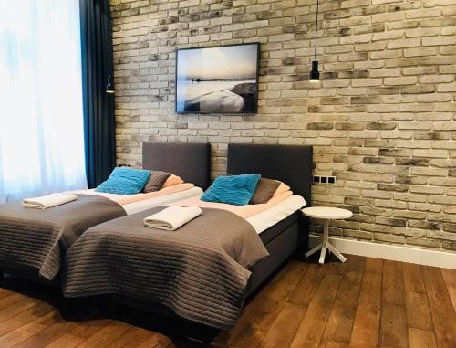 two beds in a room with a brick wall at Victus Apartamenty, Apartament Omega in Sopot