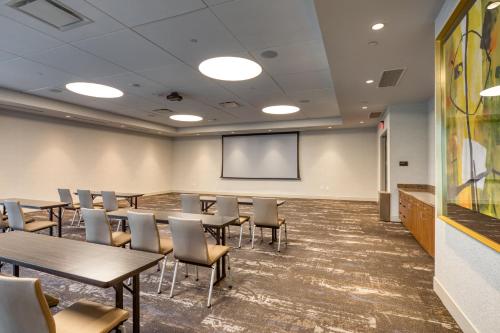 a conference room with tables and chairs and a screen at Holiday Inn Express & Suites - Charlotte - South End by IHG in Charlotte