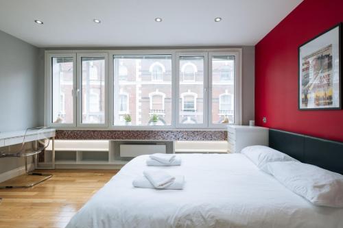 1 dormitorio con cama blanca y pared roja en Amazing Studio Flat in Central London. Stylish & Cosy, en Londres