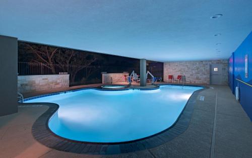 una gran piscina con iluminación azul en un edificio en Holiday Inn Express & Suites Austin NW - Four Points, an IHG Hotel en Four Points