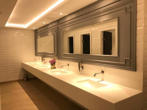 a bathroom with three sinks and two mirrors at The Nishat Hotel Johar Town in Lahore