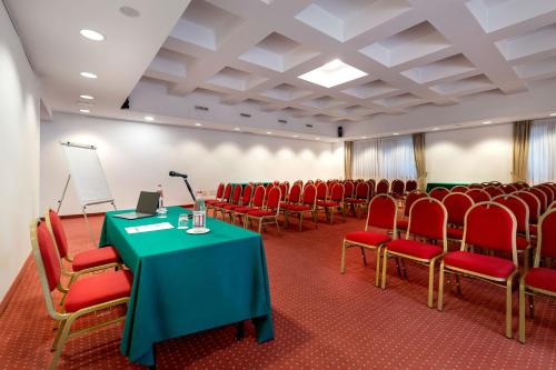 a conference room with red chairs and a table with a microphone at Best Western Cavalieri Della Corona in Cardano al Campo