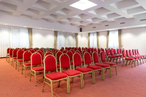 a large room with red chairs and curtains at Best Western Cavalieri Della Corona in Cardano al Campo