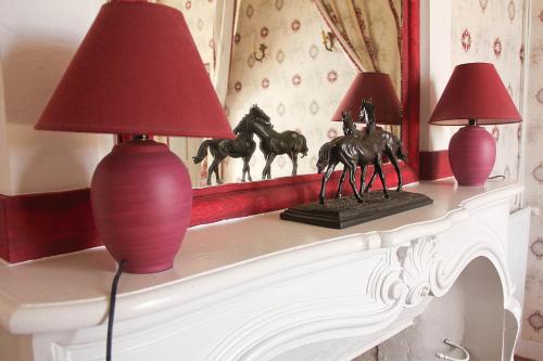 a fireplace mantle with two lamps and a statue of horses on it at Chambres d'hôtes au Château de Gizeux in Gizeux