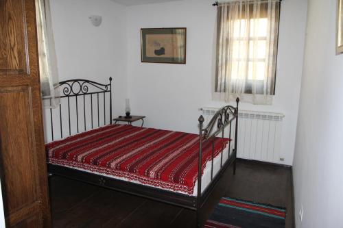 1 dormitorio con 1 cama con edredón rojo en New Bakalov House en Bozhentsi