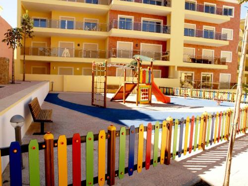 a fence with a playground in front of a building at HENRI'S APARTMENTS - Pátio do Convento in Lagos