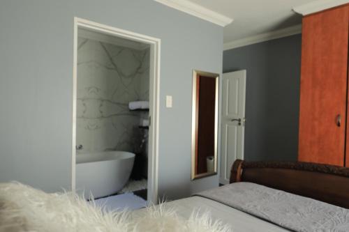 a bedroom with a bath tub and a bed with a mirror at The View - Luxury Apartment in eMalahleni