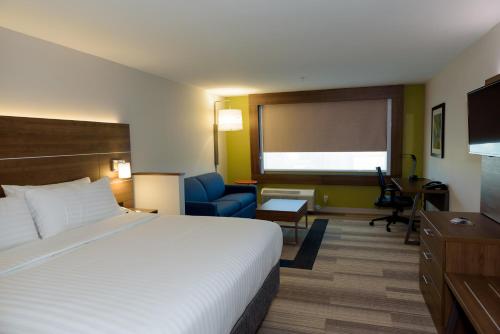 a hotel room with a large bed and a chair at Holiday Inn Express & Suites McKinney - Frisco East by IHG in McKinney
