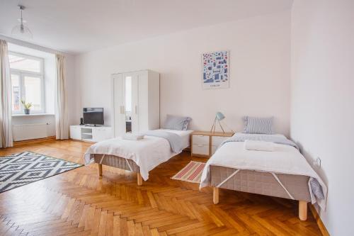 two beds in a room with white walls and wood floors at Apartamenty Krakowskie 36 Lublin - Single One in Lublin