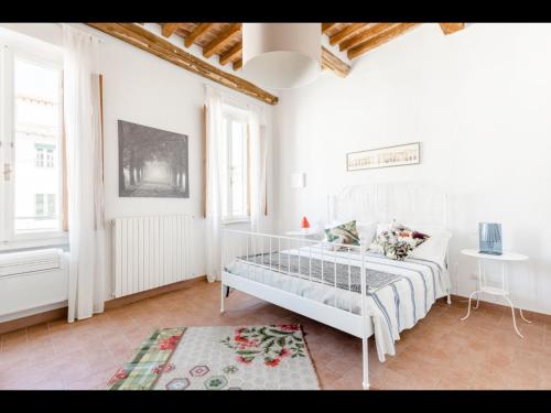 Habitación blanca con cama y alfombra en Michael's Home - Cozy apartment in the heart of Lucca, en Lucca