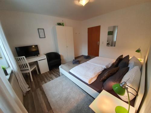 a bedroom with a bed and a desk and a television at Pension Reinhardshäusle in Reinhardshausen
