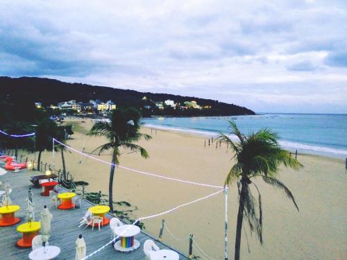 a sandy beach with palm trees and the ocean at 湛藍海岸民宿 Azure-零泊預約居-這個夏天有點藍--墾丁南灣沙灘-可包棟-國旅卡 in Nanwan