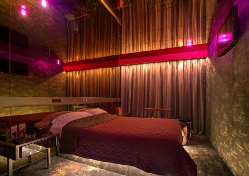 a bedroom with a bed in a room with purple lights at ALFA HOTEL in Skaramangás