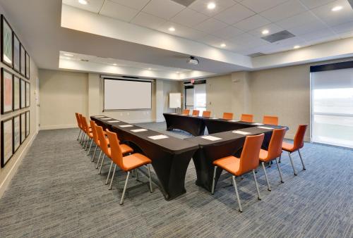 a conference room with a large black table and orange chairs at Holiday Inn Express & Suites Irving Conv Ctr - Las Colinas by IHG in Irving