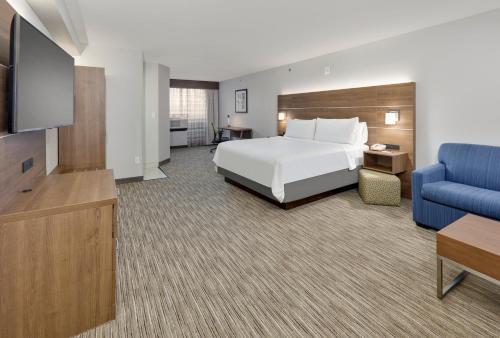 a hotel room with a bed and a blue couch at Holiday Inn Express & Suites Irving Conv Ctr - Las Colinas by IHG in Irving