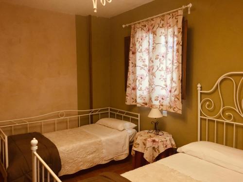 1 dormitorio con 2 camas y una ventana con cortina en La Casa del Cartero Pablo en Saldaña de Ayllón