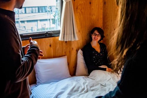 een vrouw op een bed in een kamer bij Focus Kuramae in Tokyo