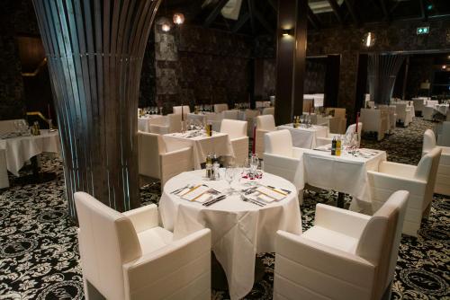 a dining room with white tables and white chairs at Le Grand Hôtel Le Touquet-Paris-Plage in Le Touquet-Paris-Plage