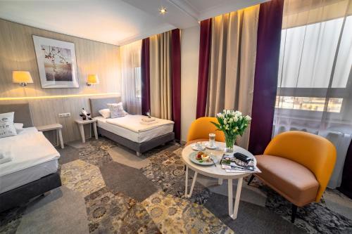 ルブリンにあるホテル ヴィクトリアのベッド、テーブル、椅子が備わるホテルルームです。