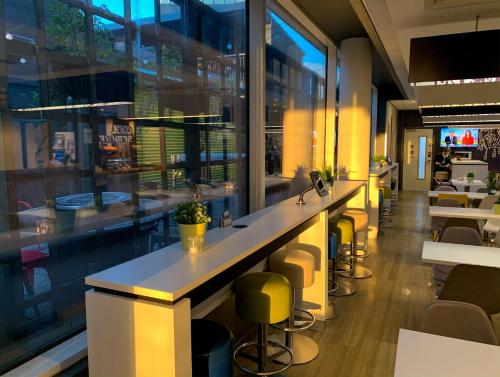 a bar in a restaurant with yellow stools at ibis budget Belfast City Centre in Belfast