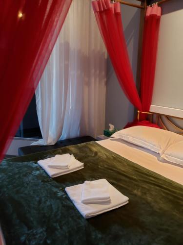 a bedroom with two beds with red curtains and towels at Biên Hòa Hotel in Bien Hoa